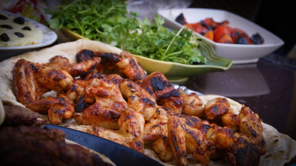 A close-up of grilled chicken wings served with fresh herbs and vegetables, perfect for culinary presentations.