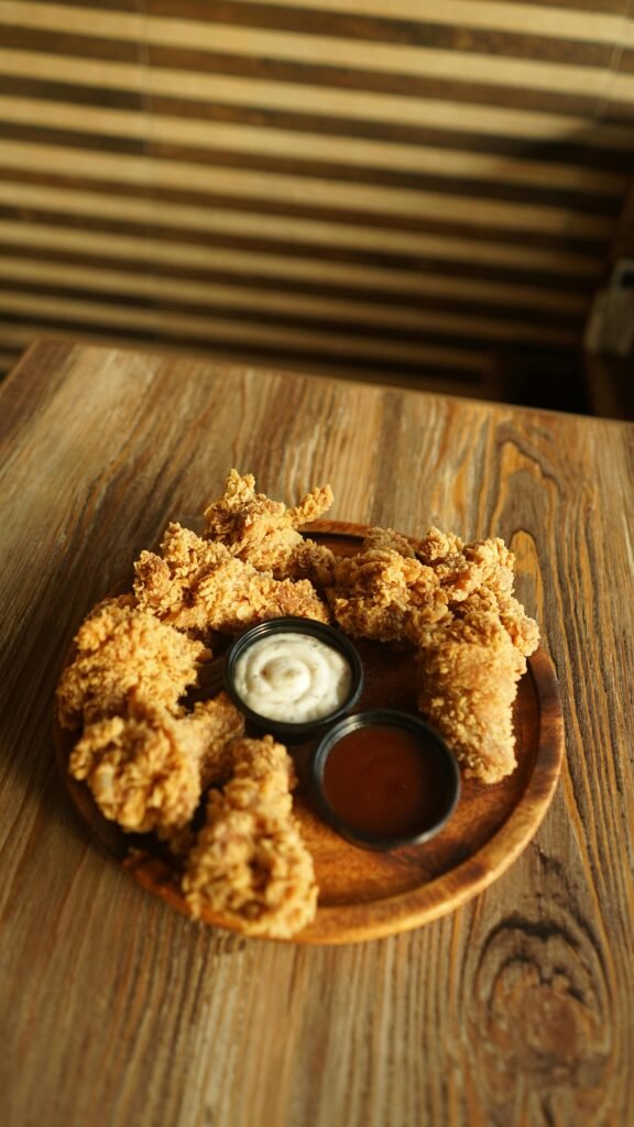 Delicious crispy fried chicken served with two tasty dipping sauces on a wooden plate.
